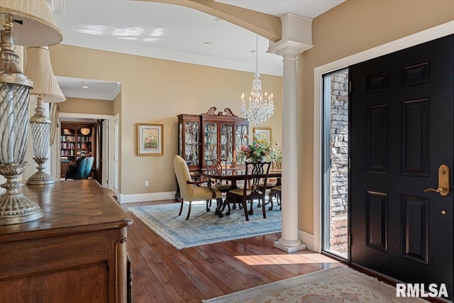 entrance foyer with baseboards, ornamental molding, decorative columns, an inviting chandelier, and hardwood / wood-style flooring
