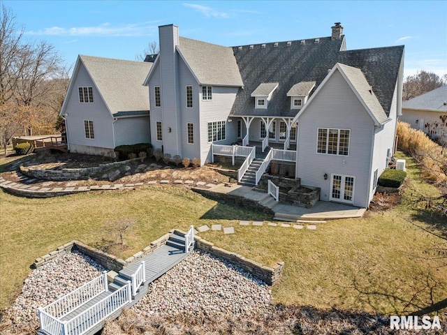rear view of property featuring a patio, stairway, a chimney, french doors, and a lawn