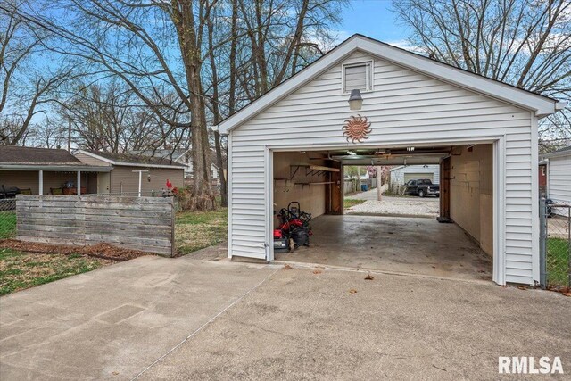 detached garage featuring fence and concrete driveway