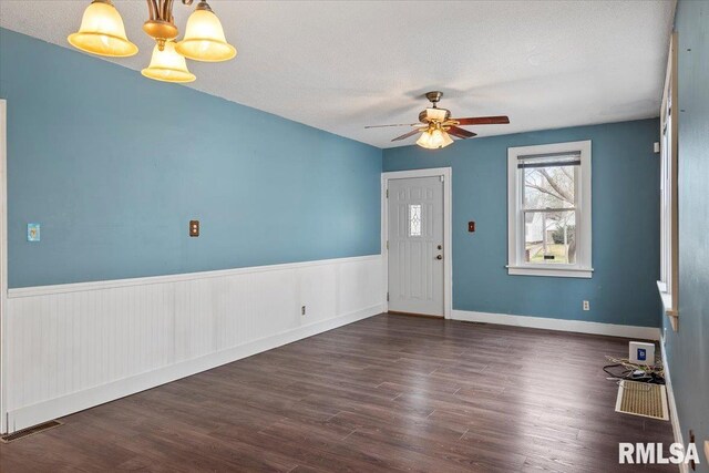 entrance foyer featuring dark wood-type flooring, visible vents, a ceiling fan, and wainscoting