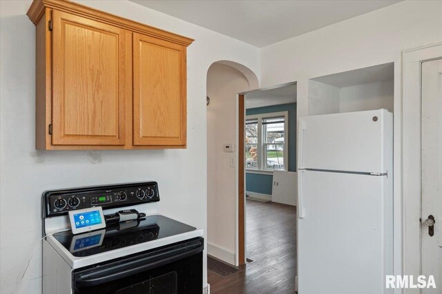 kitchen featuring dark wood-type flooring, electric stove, baseboards, and freestanding refrigerator