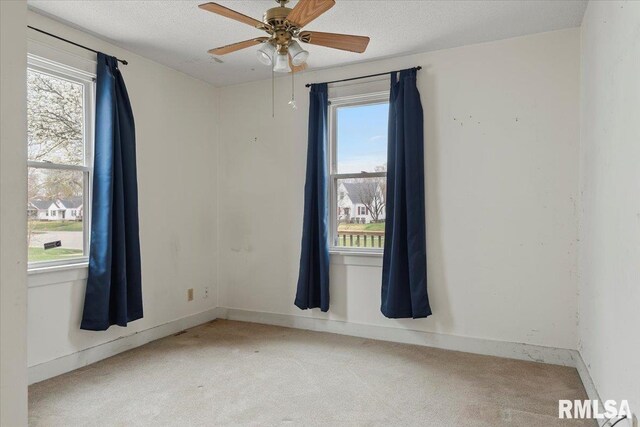 spare room with light carpet, baseboards, a ceiling fan, and a healthy amount of sunlight