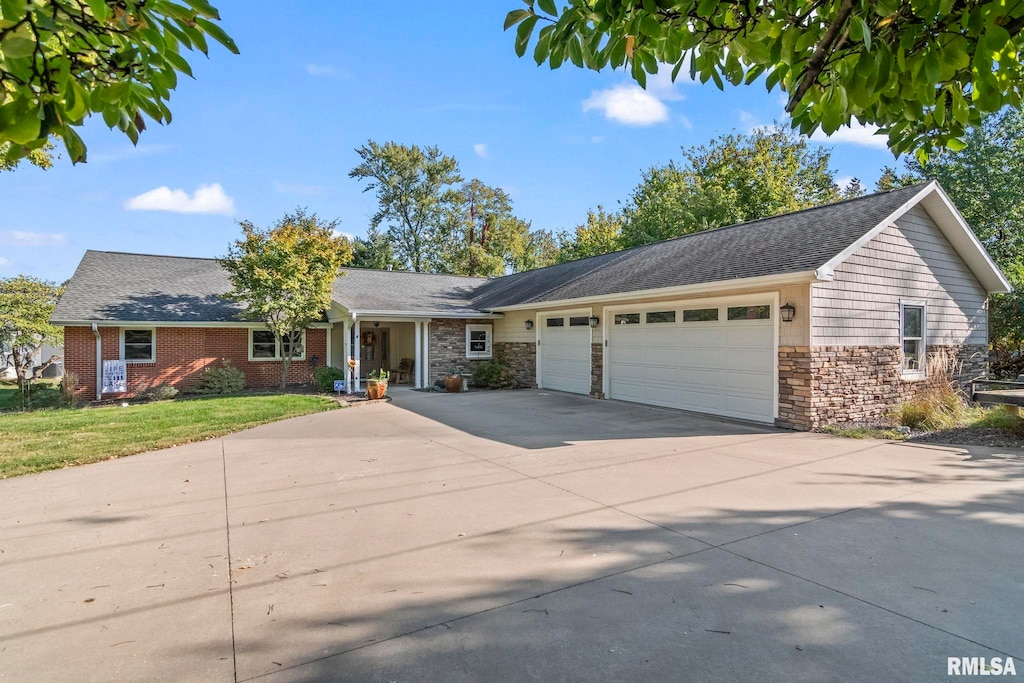 single story home featuring an attached garage, concrete driveway, a front yard, and stone siding