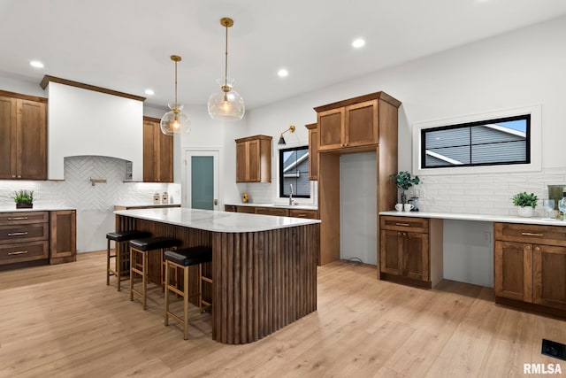5819 Kelley Pointe Dr, Springfield, IL 62711 - kitchen featuring brown cabinetry, decorative backsplash, light wood-style floors, recessed lighting, and a sink