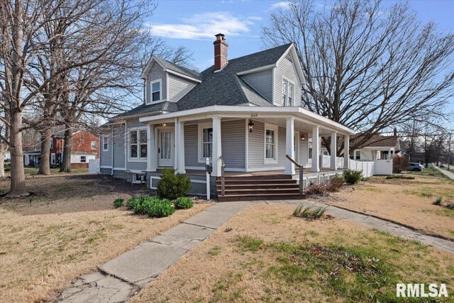 view of front of house with covered porch, a shingled roof, and a chimney
