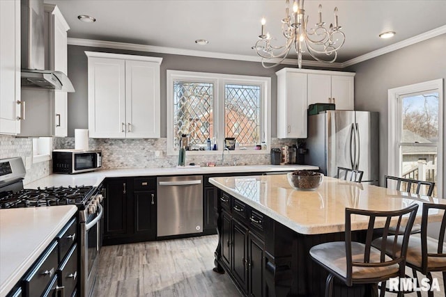 kitchen featuring white cabinetry, stainless steel appliances, dark cabinets, and a breakfast bar
