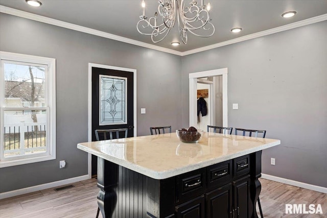 kitchen with baseboards, visible vents, dark cabinets, and a kitchen breakfast bar