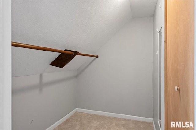 walk in closet featuring light colored carpet and lofted ceiling