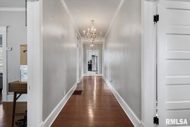 hall with a notable chandelier, crown molding, dark wood-style floors, baseboards, and visible vents
