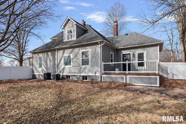 back of property with central air condition unit, a chimney, and fence