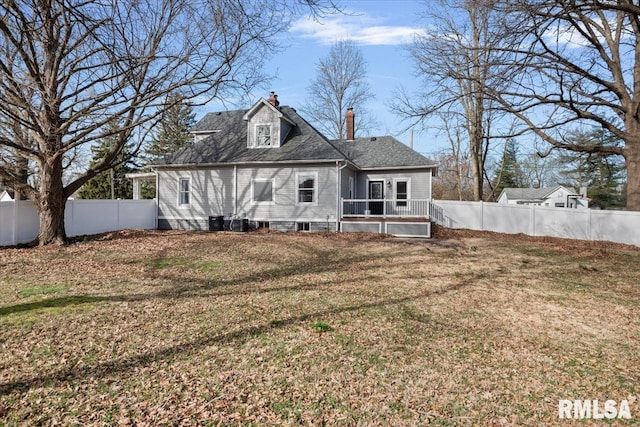 back of house with a fenced backyard, a lawn, and a chimney