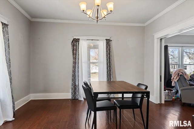 dining space with wood-type flooring, a notable chandelier, crown molding, and baseboards