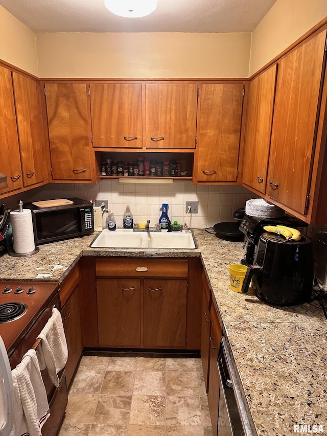 kitchen with tasteful backsplash, a sink, brown cabinetry, black microwave, and dishwasher