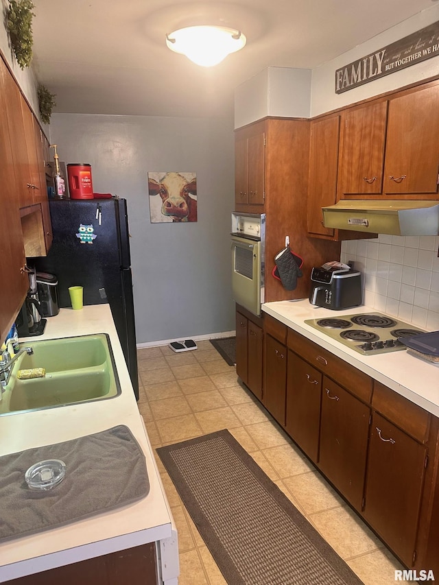kitchen with under cabinet range hood, electric stovetop, light countertops, and wall oven