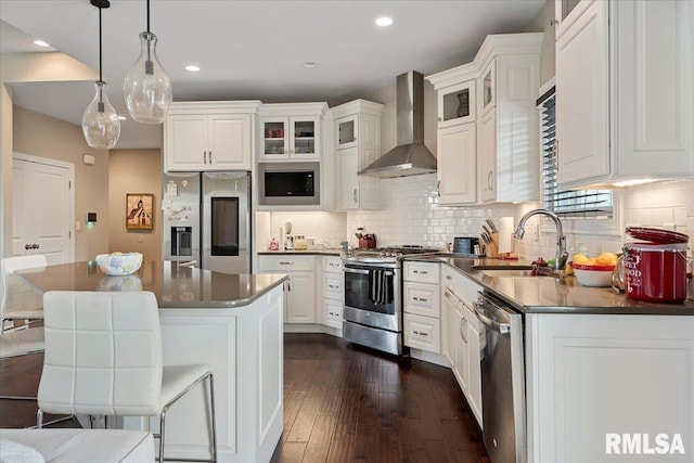 kitchen featuring a sink, wall chimney range hood, white cabinetry, and stainless steel appliances