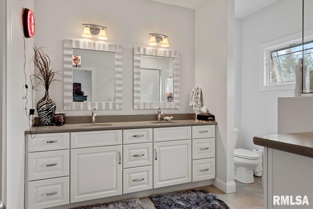 bathroom featuring a sink, toilet, double vanity, and tile patterned flooring