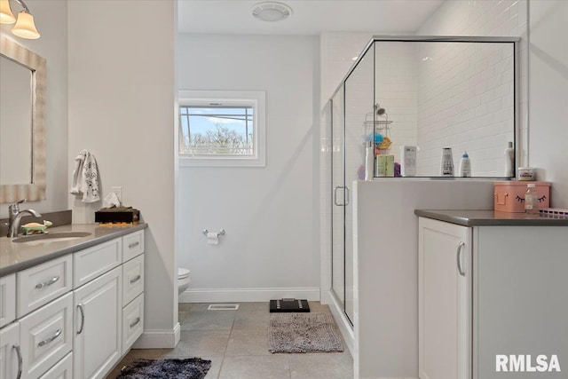 full bathroom with vanity, baseboards, a stall shower, tile patterned flooring, and toilet