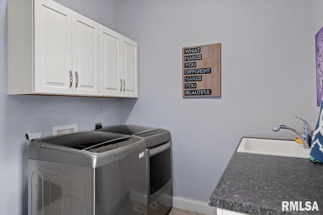 laundry room with cabinet space, baseboards, washer and dryer, and a sink