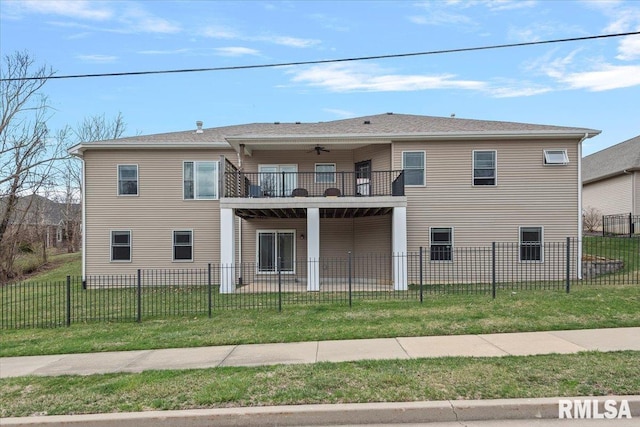 view of front of house featuring a front yard, a ceiling fan, a fenced front yard, and a balcony