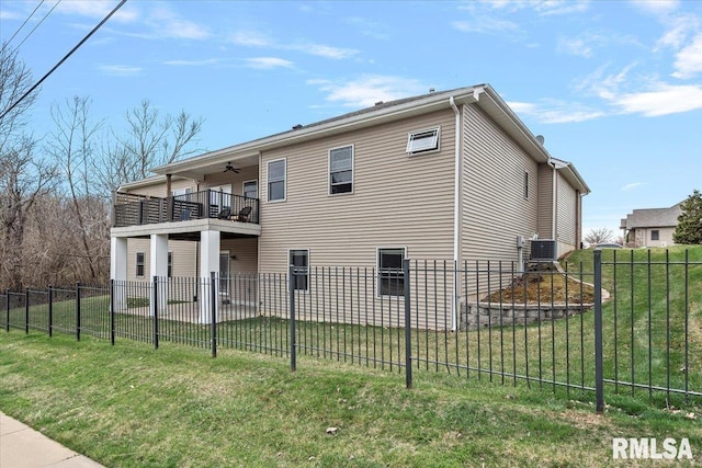 rear view of house featuring a balcony, a ceiling fan, a fenced backyard, central AC, and a lawn