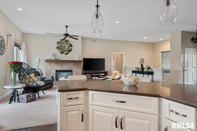 kitchen featuring open floor plan, a tile fireplace, a ceiling fan, and dark countertops