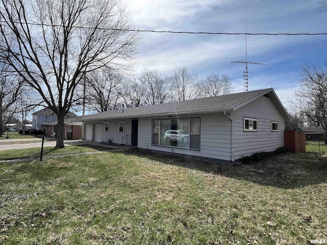 ranch-style home with a shingled roof, a garage, and a front lawn