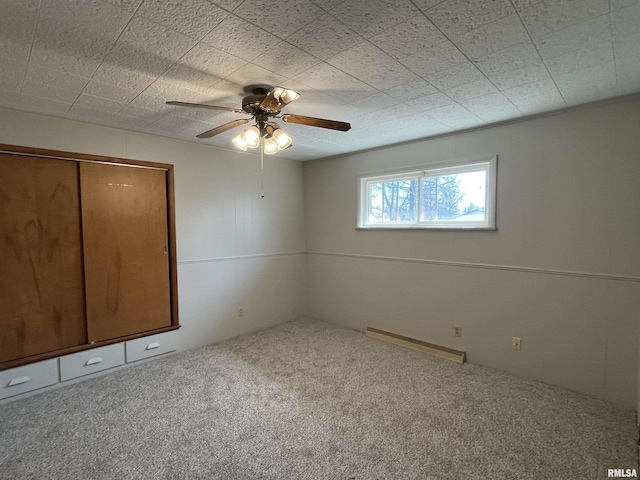 unfurnished bedroom featuring carpet, baseboard heating, a closet, and ceiling fan