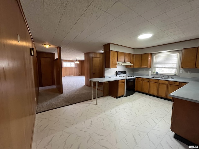 kitchen featuring gas range, marble finish floor, a sink, under cabinet range hood, and brown cabinets