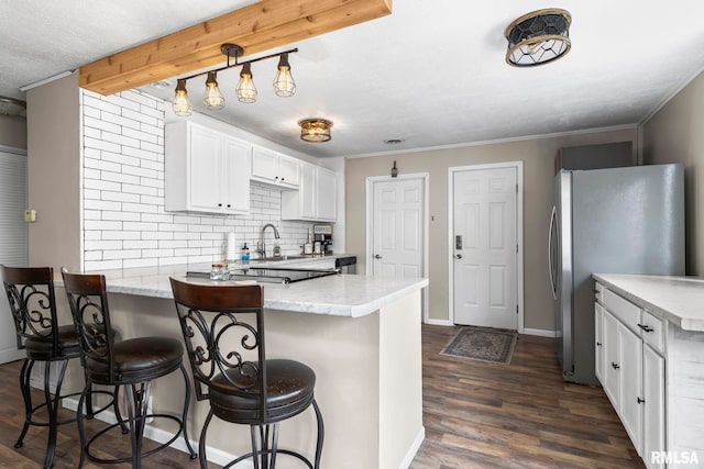 2364 E Keys Ave, Springfield, IL 62702 - kitchen with a peninsula, freestanding refrigerator, white cabinetry, dark wood finished floors, and decorative backsplash