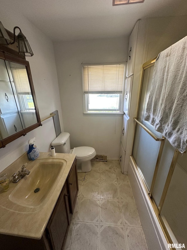 bathroom with toilet, combined bath / shower with glass door, vanity, and a healthy amount of sunlight