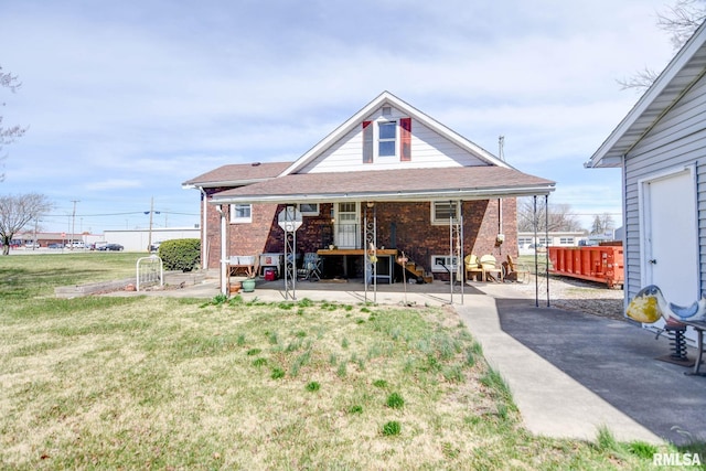 back of house with a lawn, brick siding, and a patio area