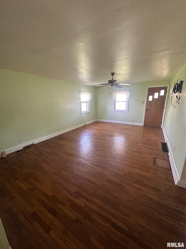 interior space with baseboards, visible vents, ceiling fan, and dark wood-style flooring