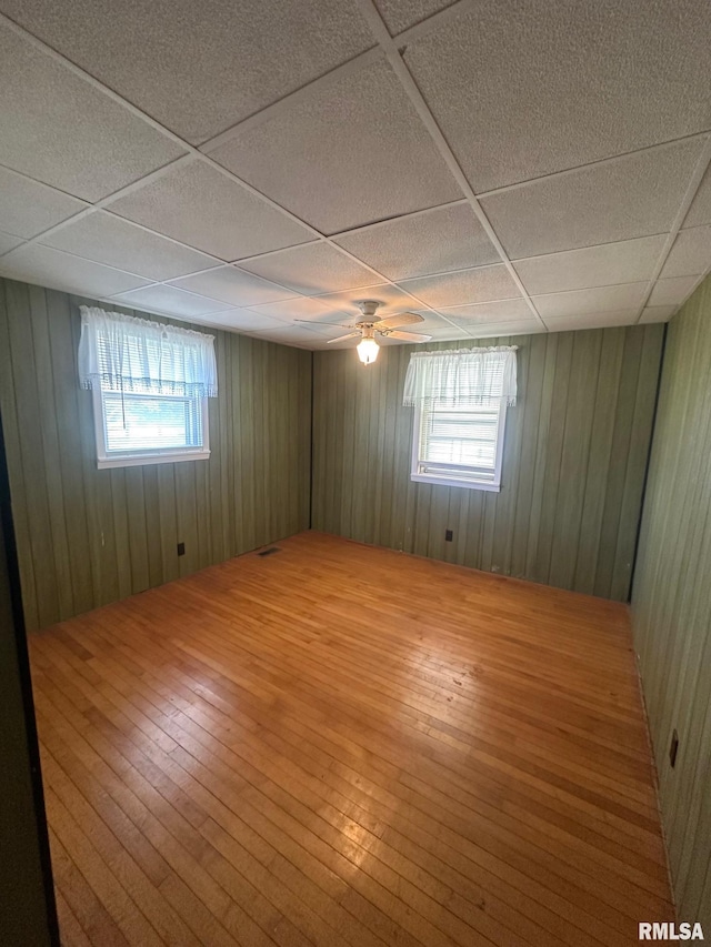 spare room featuring a paneled ceiling, hardwood / wood-style floors, and a wealth of natural light