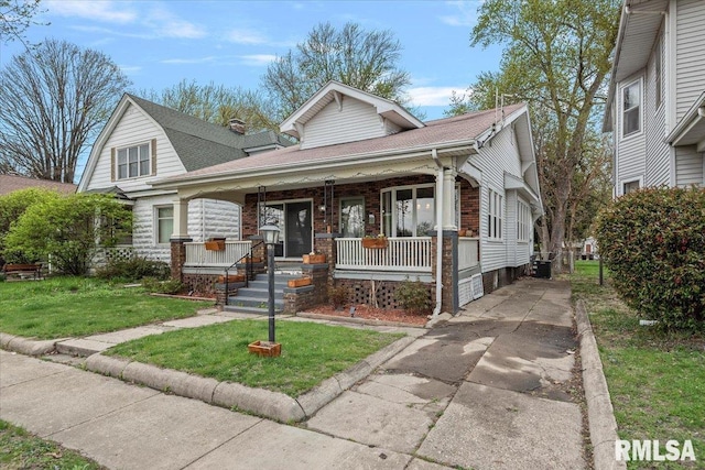 view of front of house featuring roof with shingles, central AC unit, a porch, concrete driveway, and a front yard