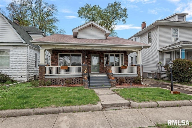 view of front of home featuring a front lawn, brick siding, and a porch