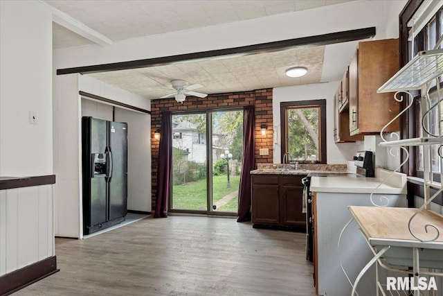 kitchen featuring light countertops, a ceiling fan, a sink, light wood-style flooring, and black fridge
