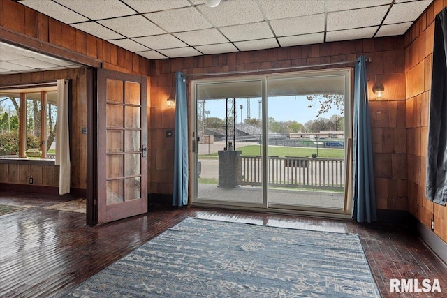 doorway featuring wood-type flooring, wooden walls, and plenty of natural light