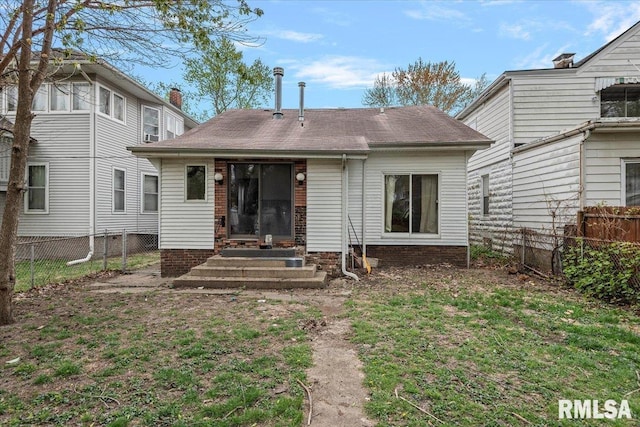 rear view of property with a fenced backyard, a shingled roof, entry steps, and a lawn