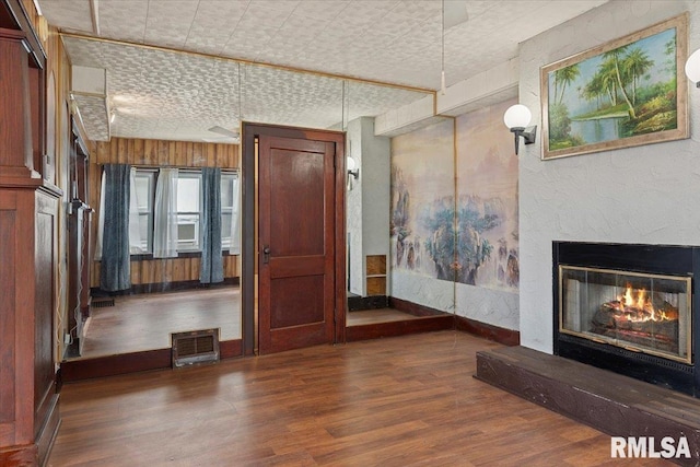 unfurnished living room with a glass covered fireplace, wood finished floors, an ornate ceiling, and visible vents