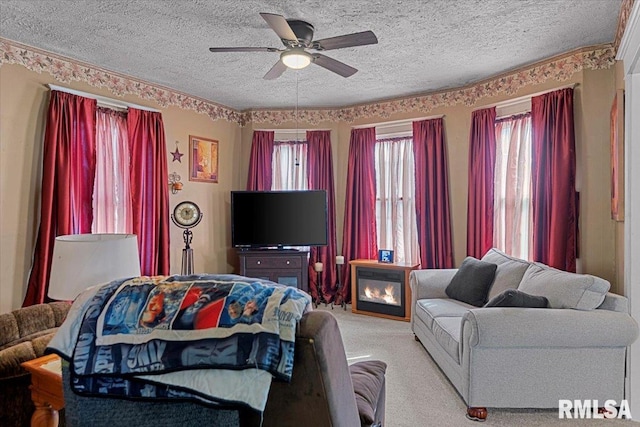 living area featuring carpet, a textured ceiling, and ceiling fan