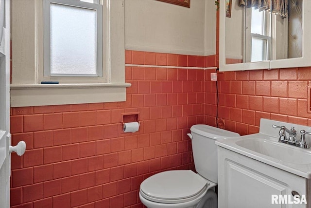 bathroom with a wainscoted wall, toilet, vanity, and plenty of natural light