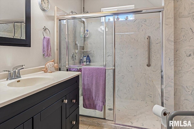 bathroom with vanity and a marble finish shower