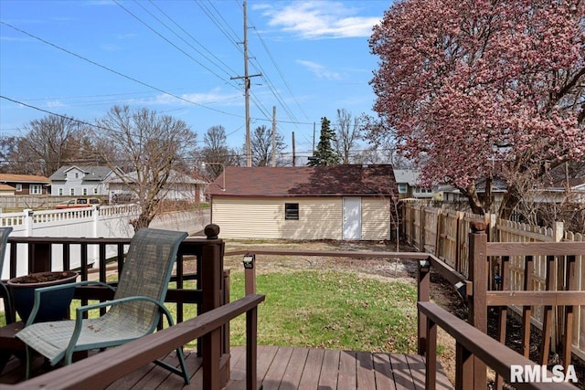 wooden deck featuring a fenced backyard, a lawn, and an outbuilding