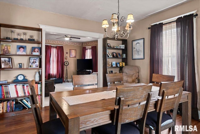 dining area with a wealth of natural light, wood finished floors, and ceiling fan with notable chandelier