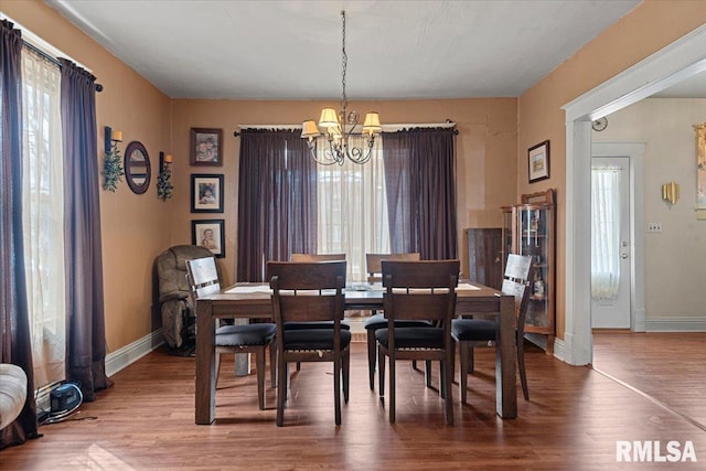 dining room with a healthy amount of sunlight, a chandelier, and wood finished floors