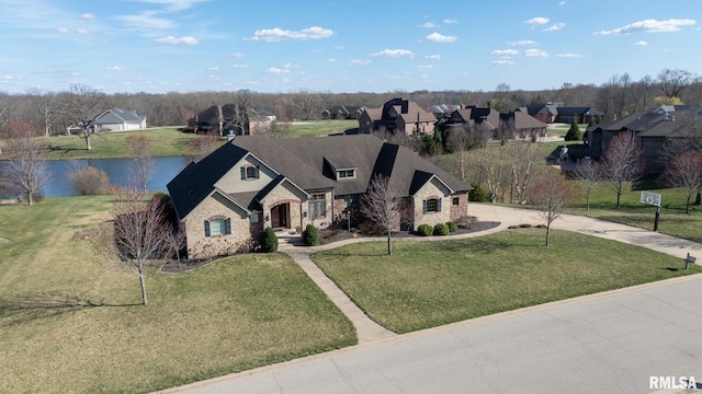 view of front of home featuring a front lawn, a water view, stone siding, and curved driveway