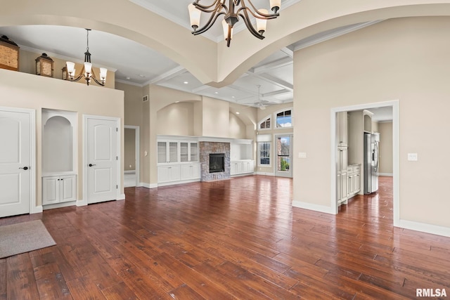 unfurnished living room with hardwood / wood-style floors, baseboards, a notable chandelier, and a stone fireplace