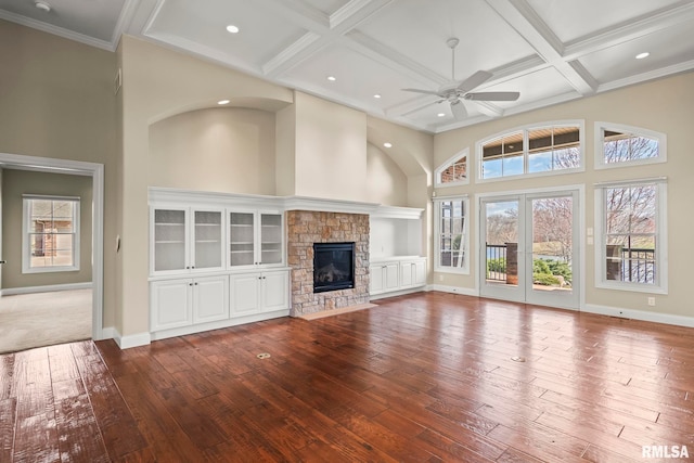 unfurnished living room with baseboards, a towering ceiling, a ceiling fan, hardwood / wood-style floors, and coffered ceiling