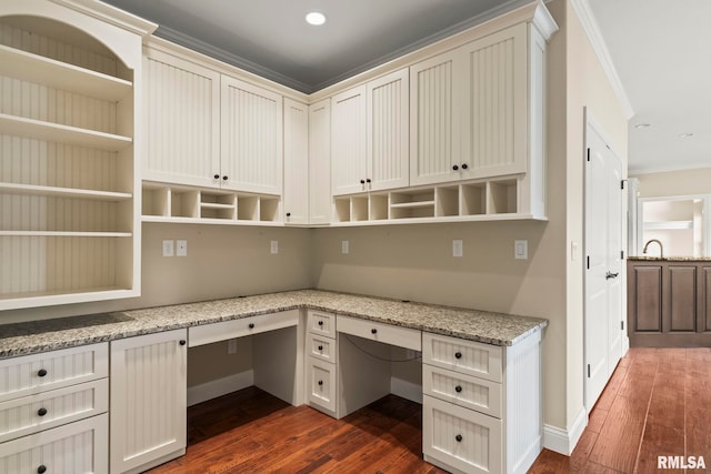 unfurnished office featuring baseboards, built in desk, ornamental molding, recessed lighting, and dark wood-type flooring