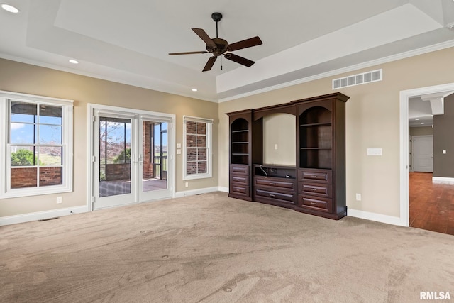 unfurnished living room featuring baseboards, a raised ceiling, carpet floors, visible vents, and a ceiling fan